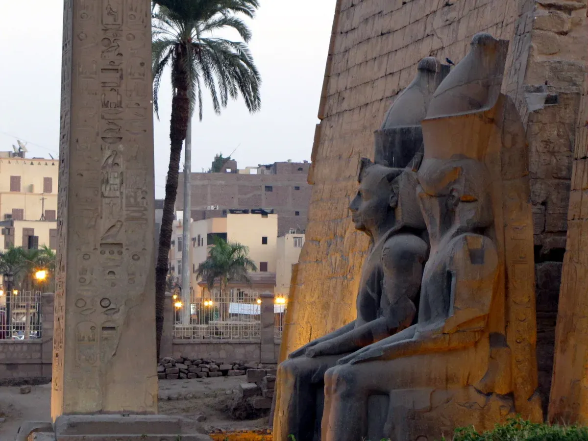 A sphinx statue and obelisk at the pylon of Luxor Temple at dusk, seen on a Valley of the Kings tour